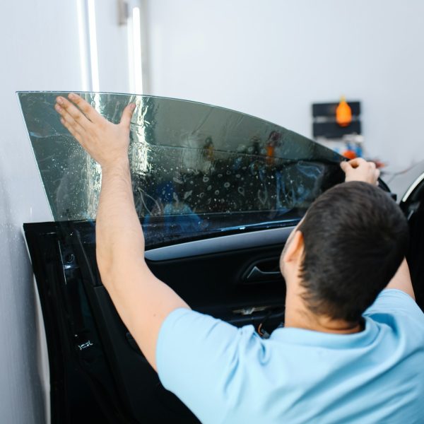 Male worker tries on sheet of car tinting